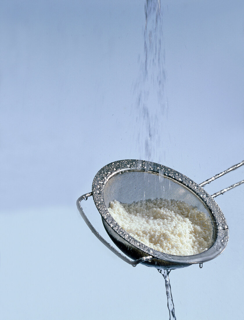 Close-up of round grain rice being washed with running water