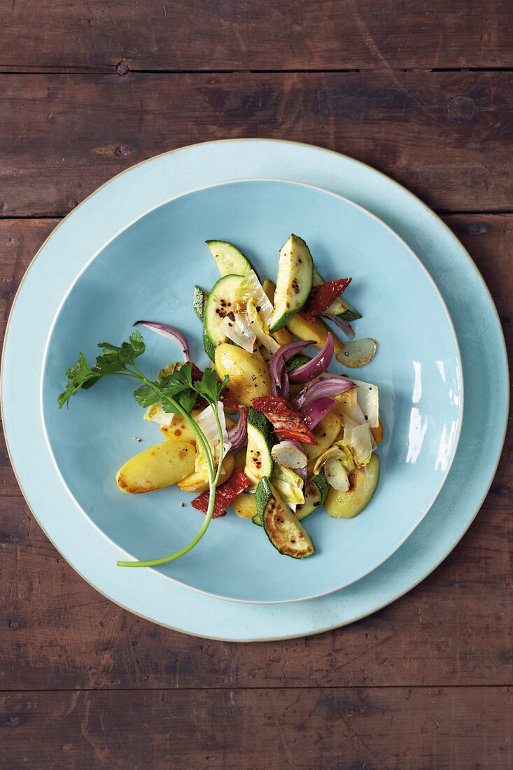 Fried potatoes and vegetables on plate, overhead view