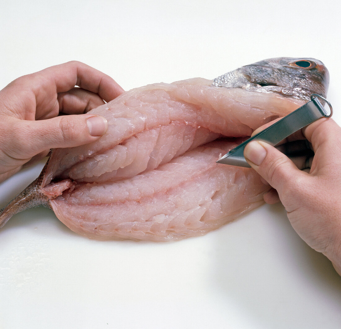 Close-up of hand removing meat bones with tweezers, step 6