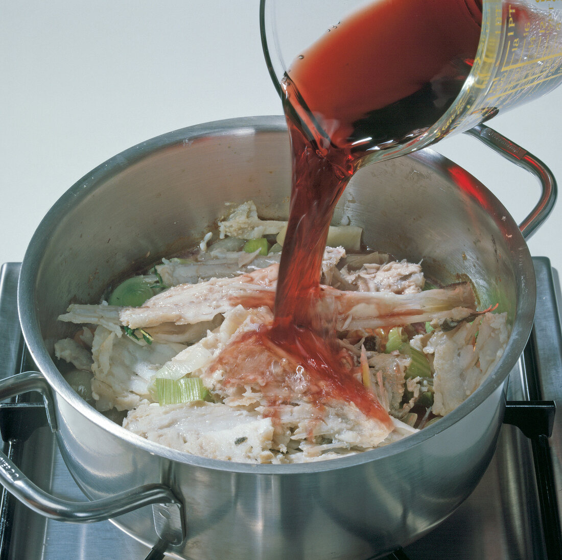 Red wine being poured in vegetables and trenches in casserole, step 3