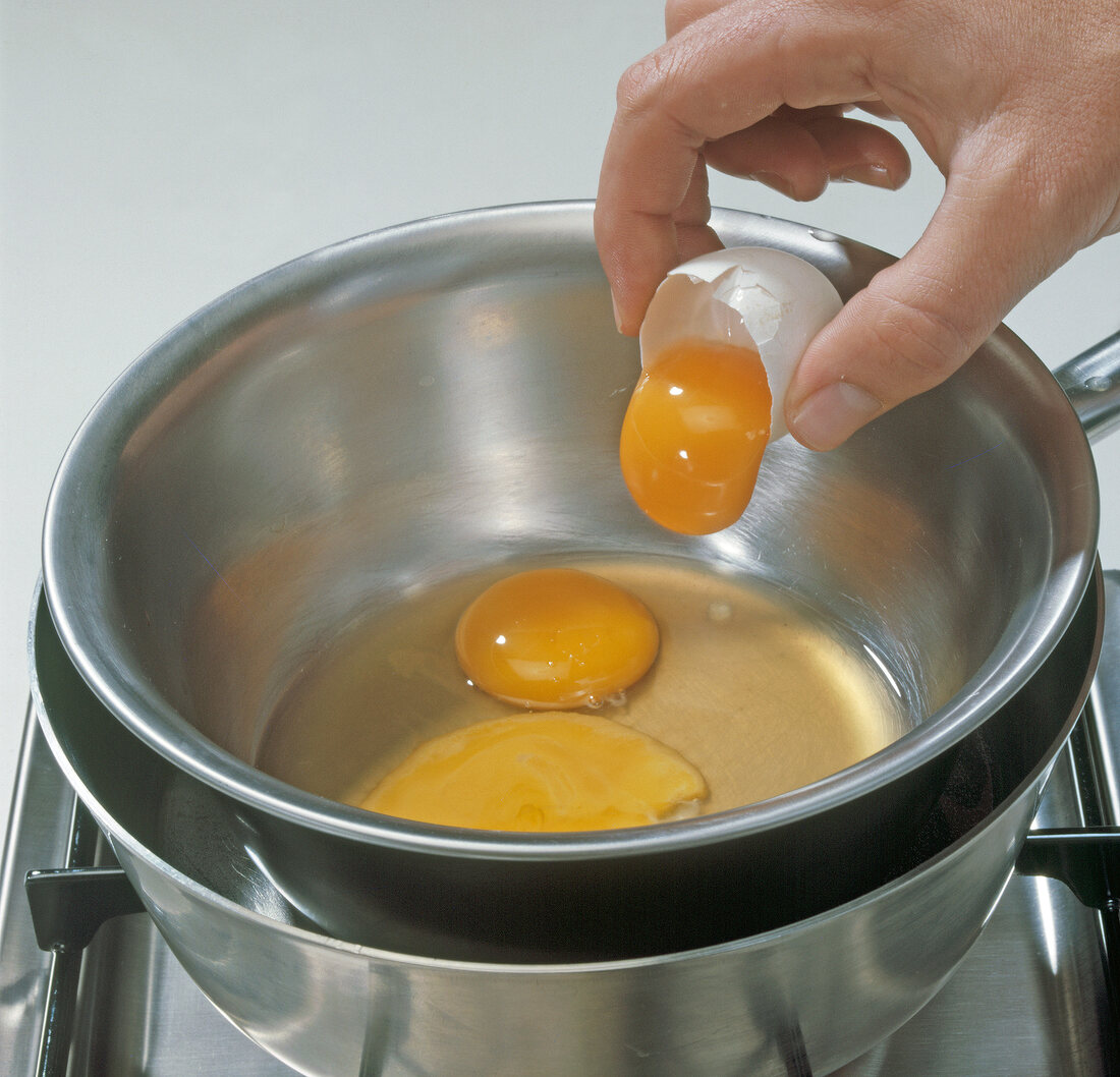 Close-up of hand adding egg yolk in bowl, step 6