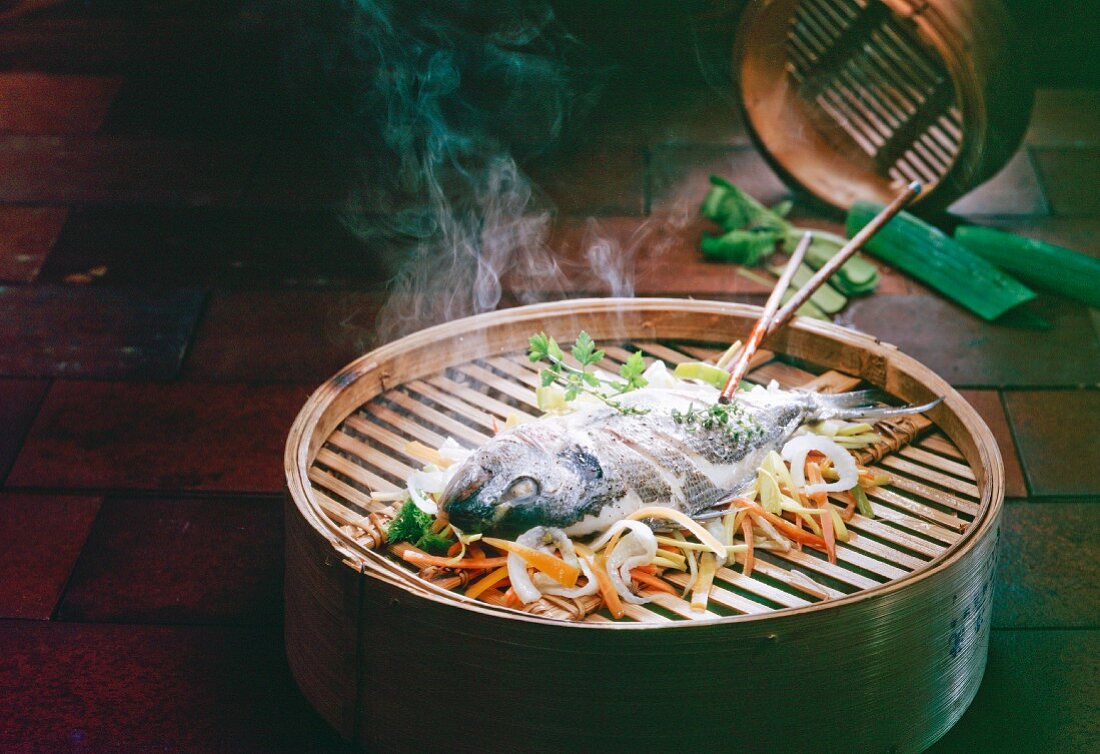 Steamed fish with vegetables in a bamboo steamer (Asia)