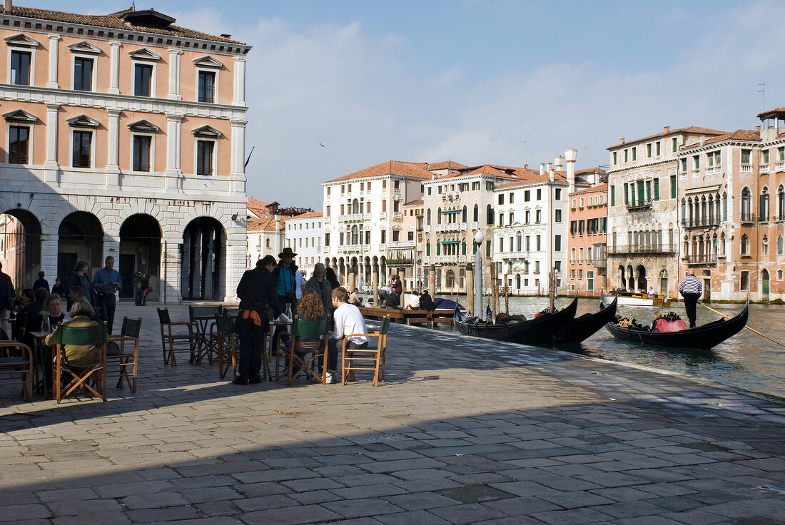 People sitting in outdoors restaurant beside Grand Canal, Venice, Italy