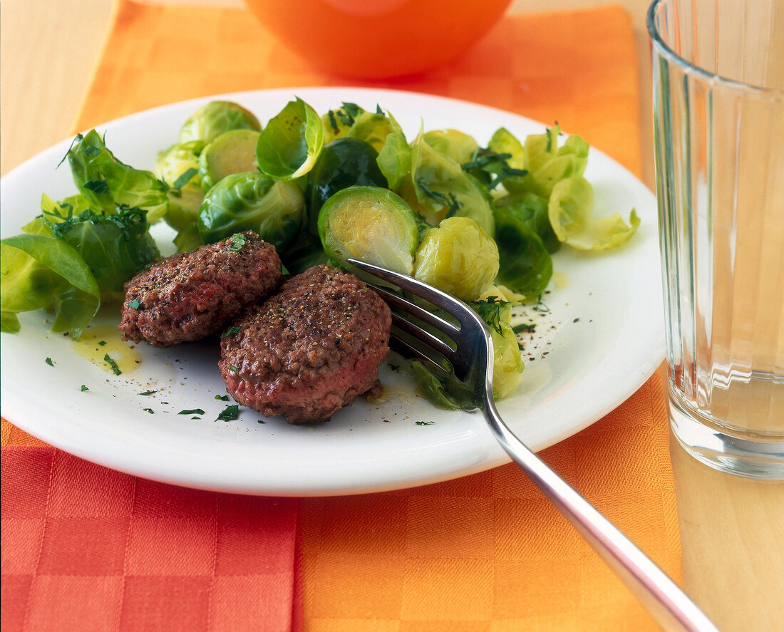 Meatballs with Brussels sprouts with fork on plate