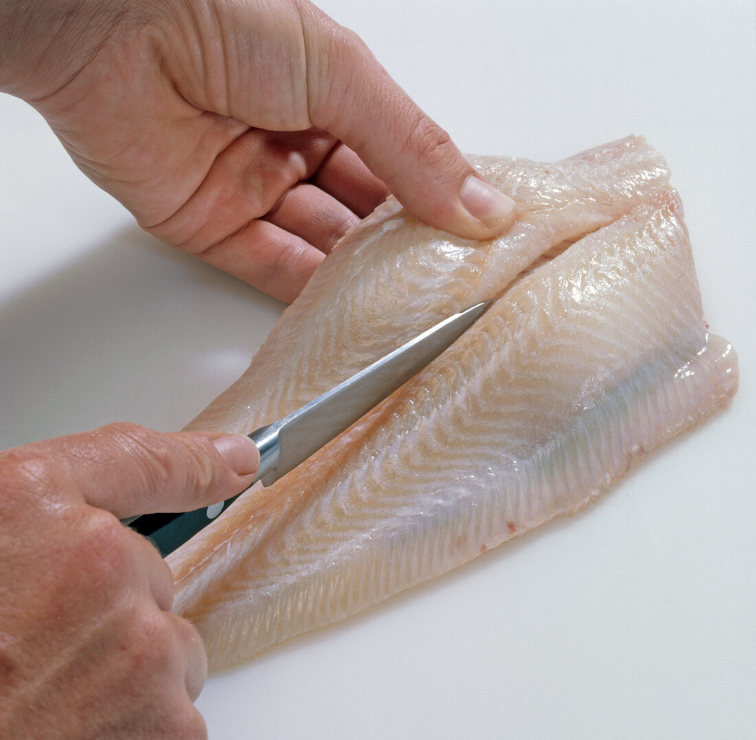 Close-up of hand making fish fillets, step 1