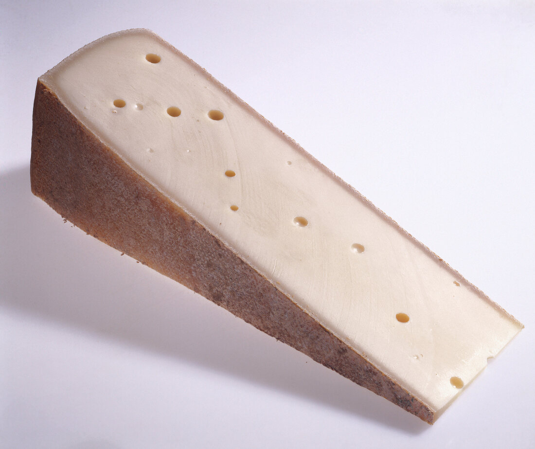 Close-up of slice of comte cheese on white background