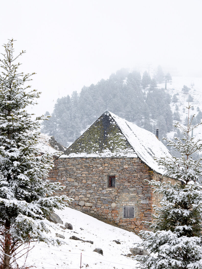 Stone house and fir trees in snow, Baqueira-Beret, Spain