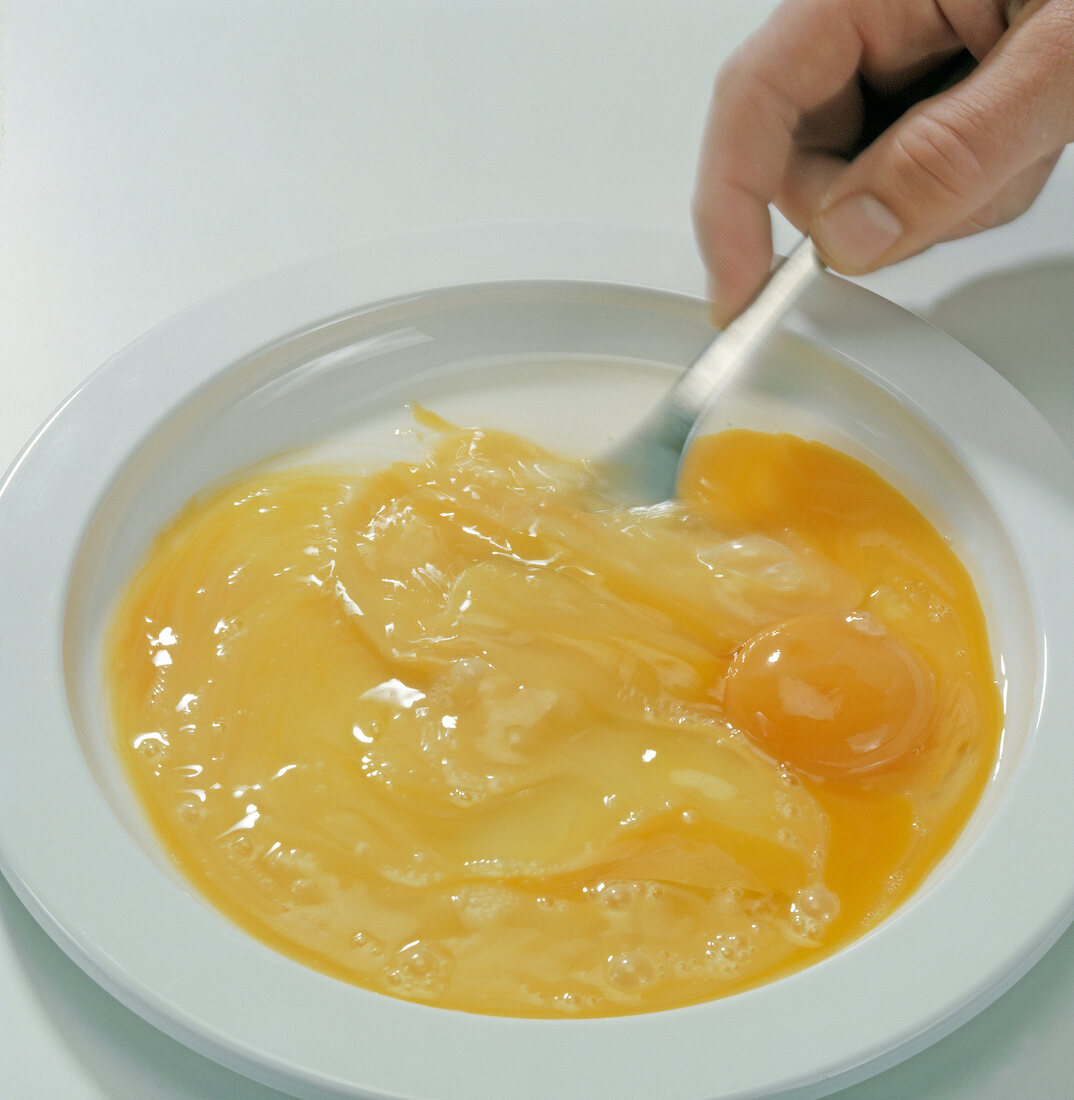 Close-up of hand beating eggs on plate, step 2