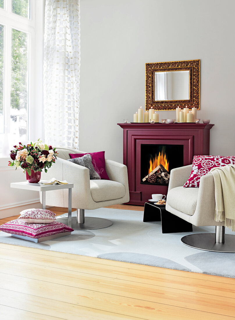 Room with white fireplace, swivel chair and brown, red and grey pillows