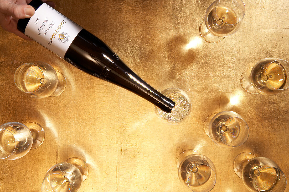 Weinflasche und Weingläser auf goldenem Untergrund, von oben