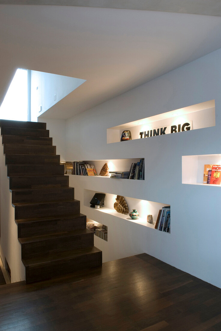 Illuminated mounting shelf next to wooden staircase in hall