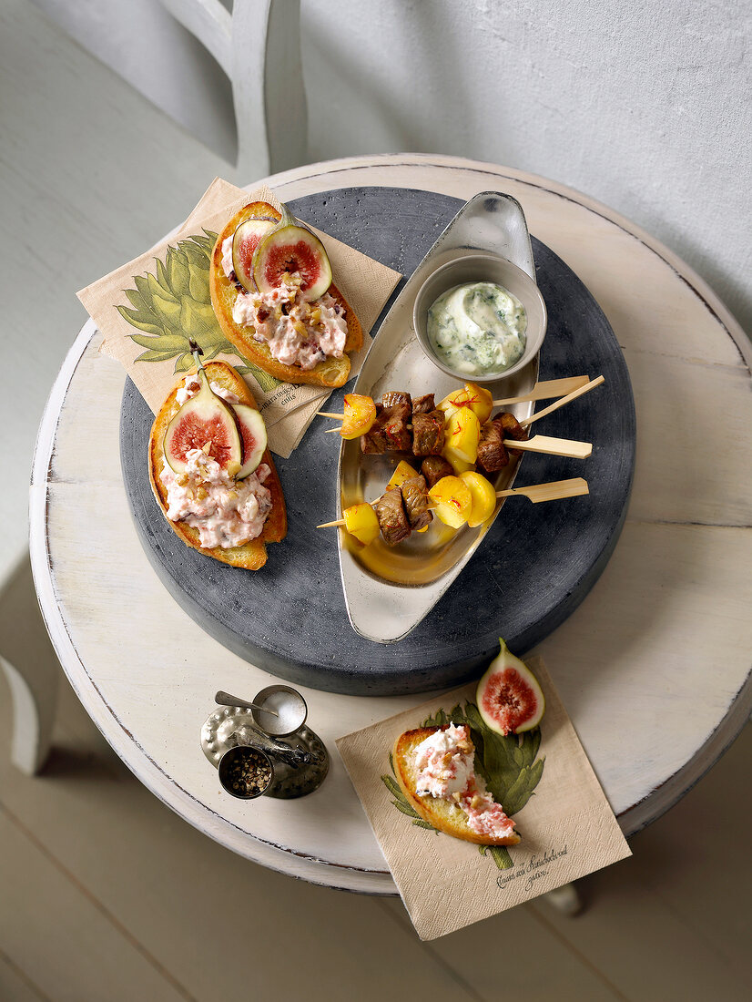 Finger food cheese with fig crostini and lamb kebabs in serving dish, overhead view