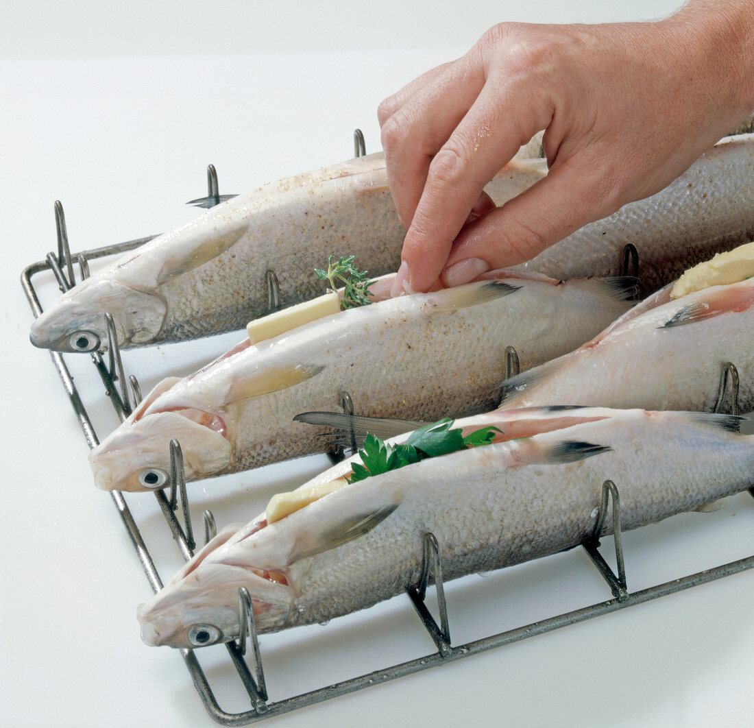 Close-up of hand filling herbs in renke fish, step 3