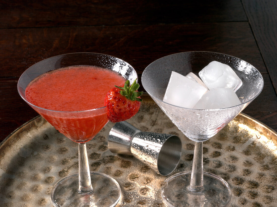 Two martini glasses with fruit martini and ice cubes