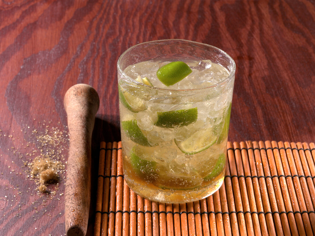 Caipirinha drink in glass with pestle besides it