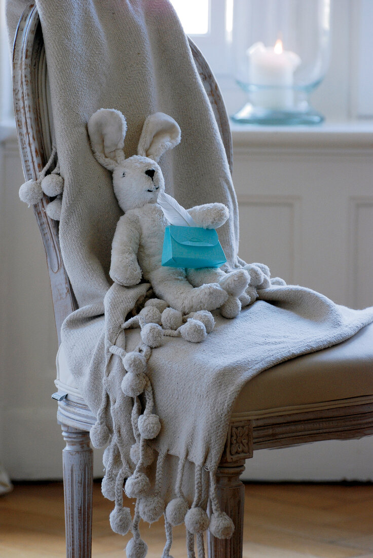 Stuffed hare with small gift on chair
