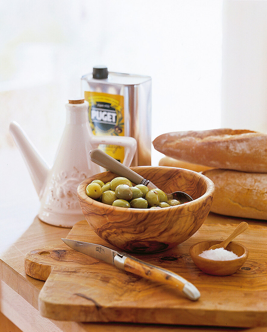 grüne Oliven in Schale, Brot, Salz, Messer