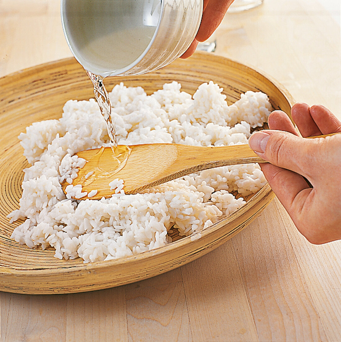 Sushi - Beträufeln von Reis mit Reisessig-Mix