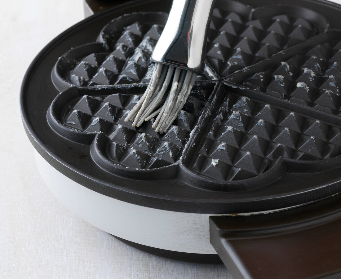Close-up of waffle maker being greased