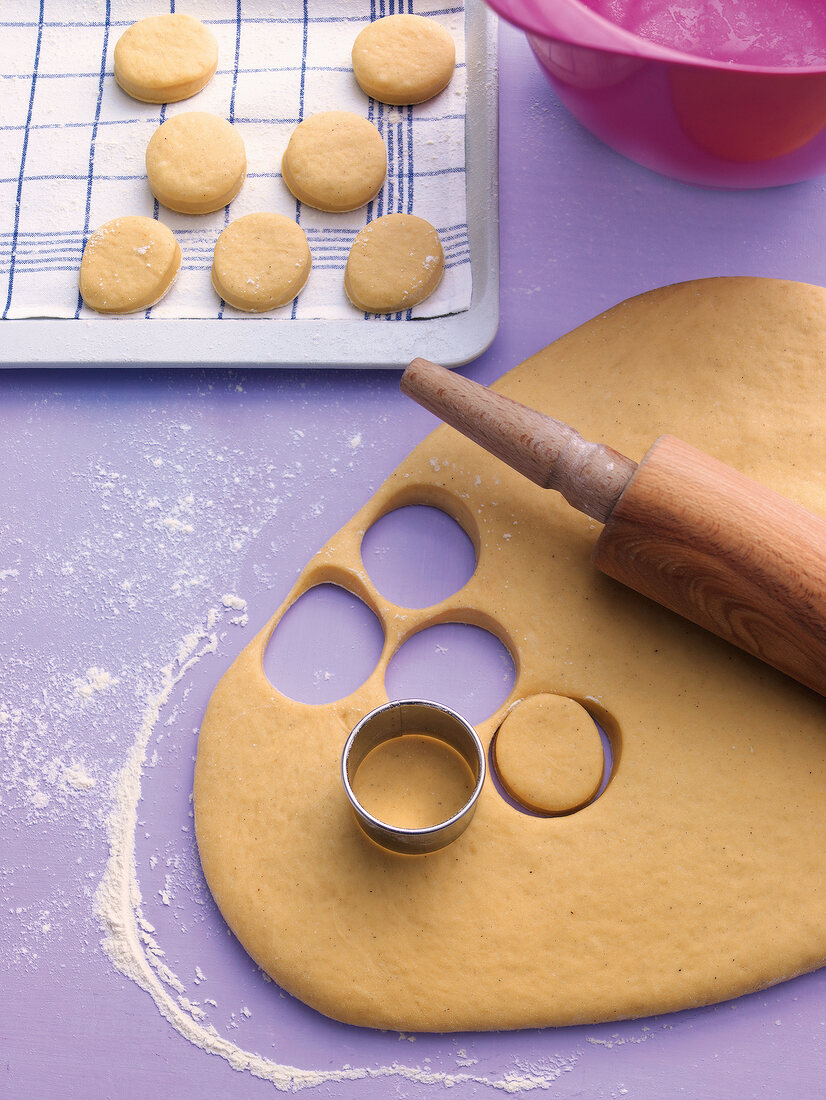 Dough being cut with cookie cutter with rolling pin for preparation of mini donuts