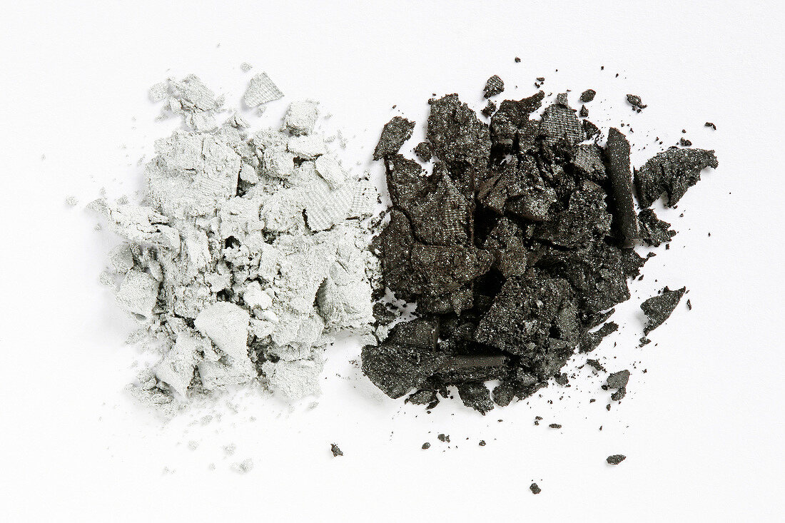 Close-up of loose dark gray and light gray eye shadow on white background