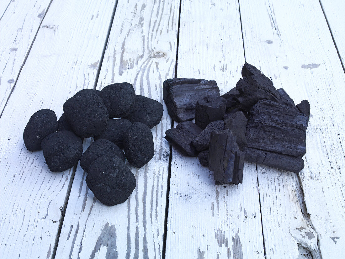 Briquettes and charcoal on wooden background