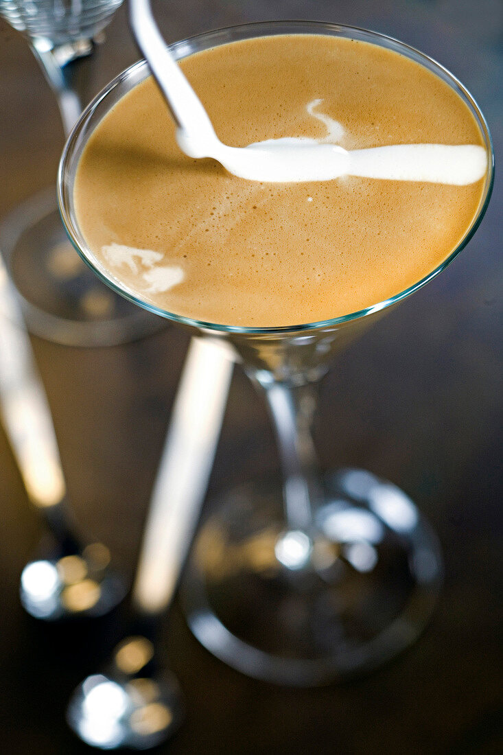 Milk being poured to espresso in cocktail glass, step 2