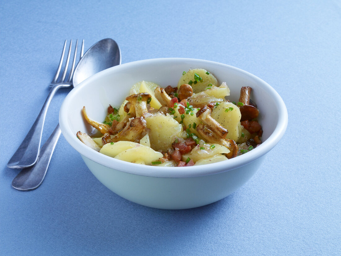 Potato salad with chanterelles and bacon in bowl