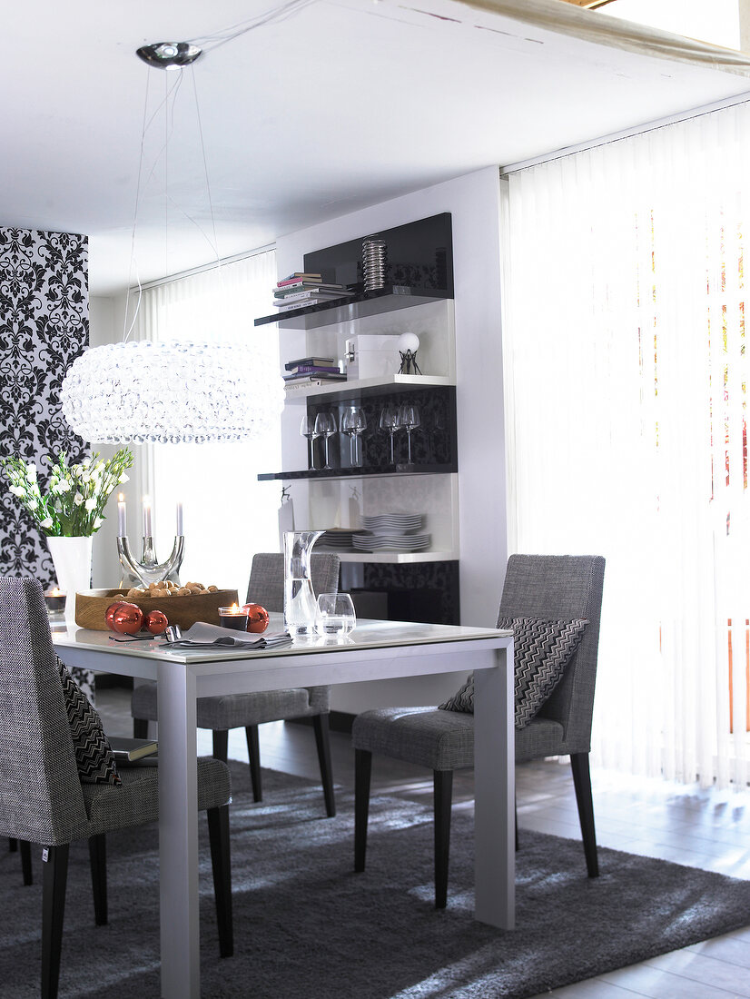 Dining room in black and white with floral motifs on wall and glass chandelier