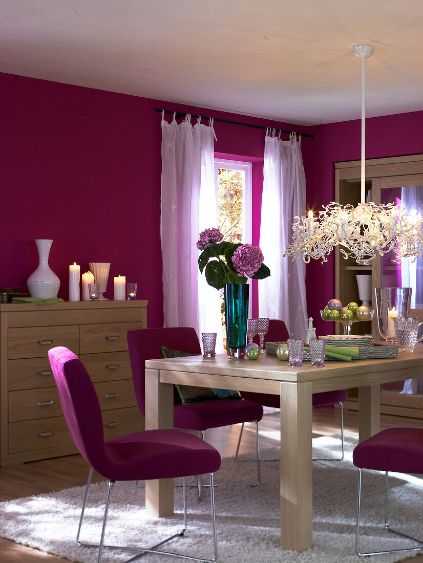 Dining room in pink with wooden furniture and green and white accessories