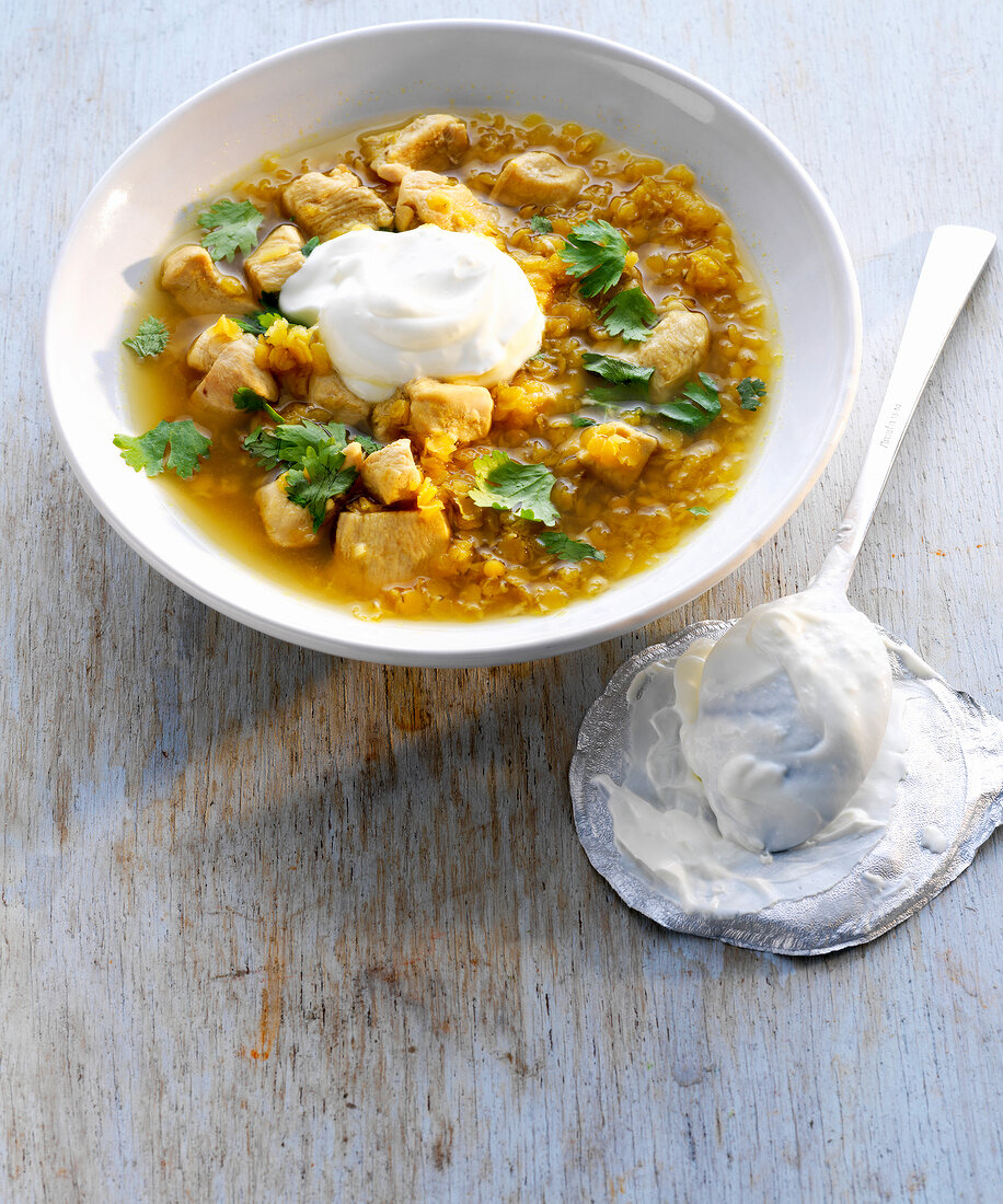Lentil soup with chicken, yogurt and coriander leaves in bowl