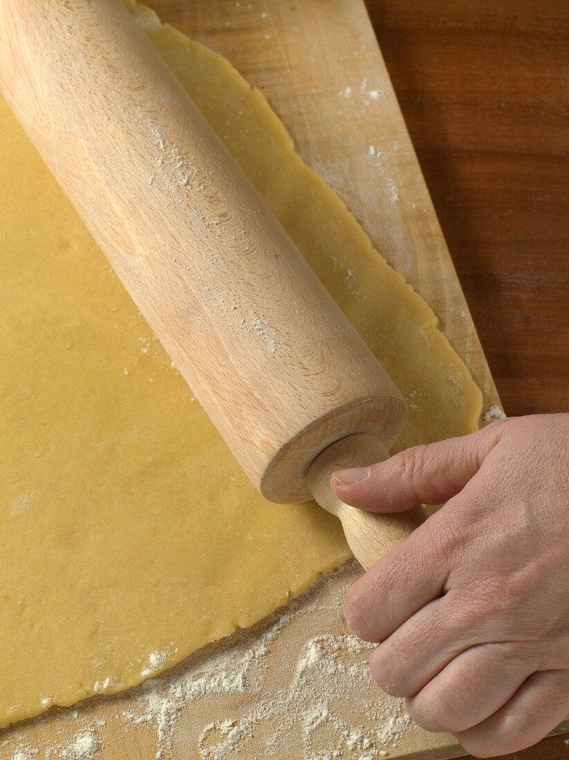 Close-up of hand rolling dough for preparation of biscuits, step 1