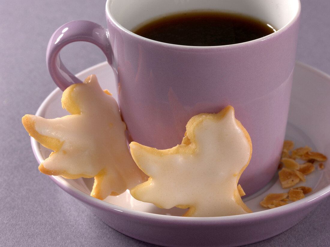 Close-up of rose biscuits and coffee in purple mug