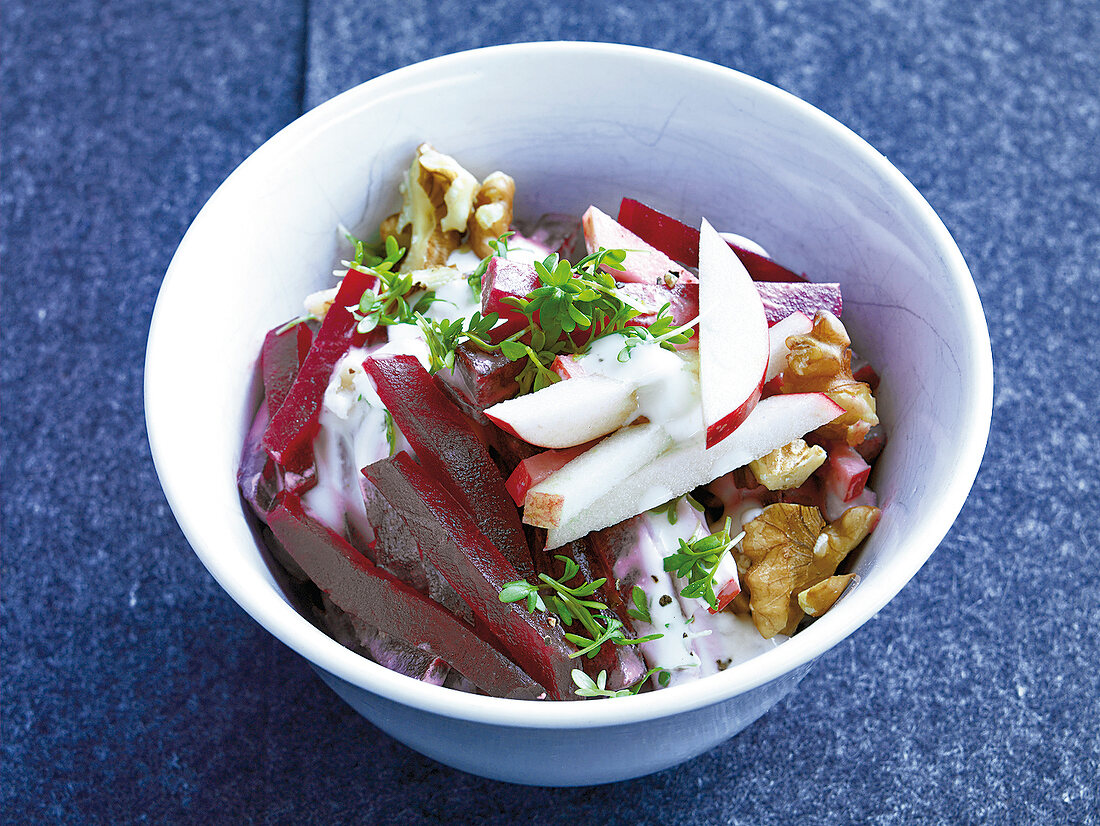 Beetroot and apple salad with walnuts and watercress in bowl