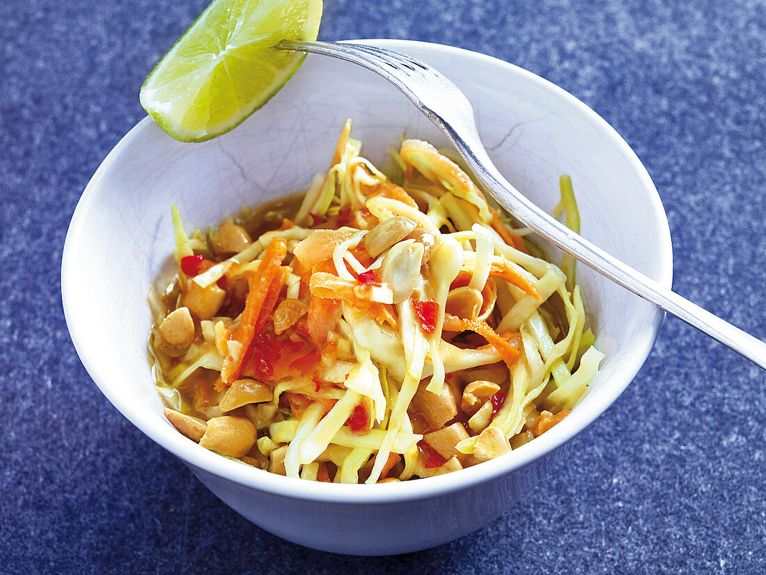 Cabbage and peanut salad with carrots and lime in bowl