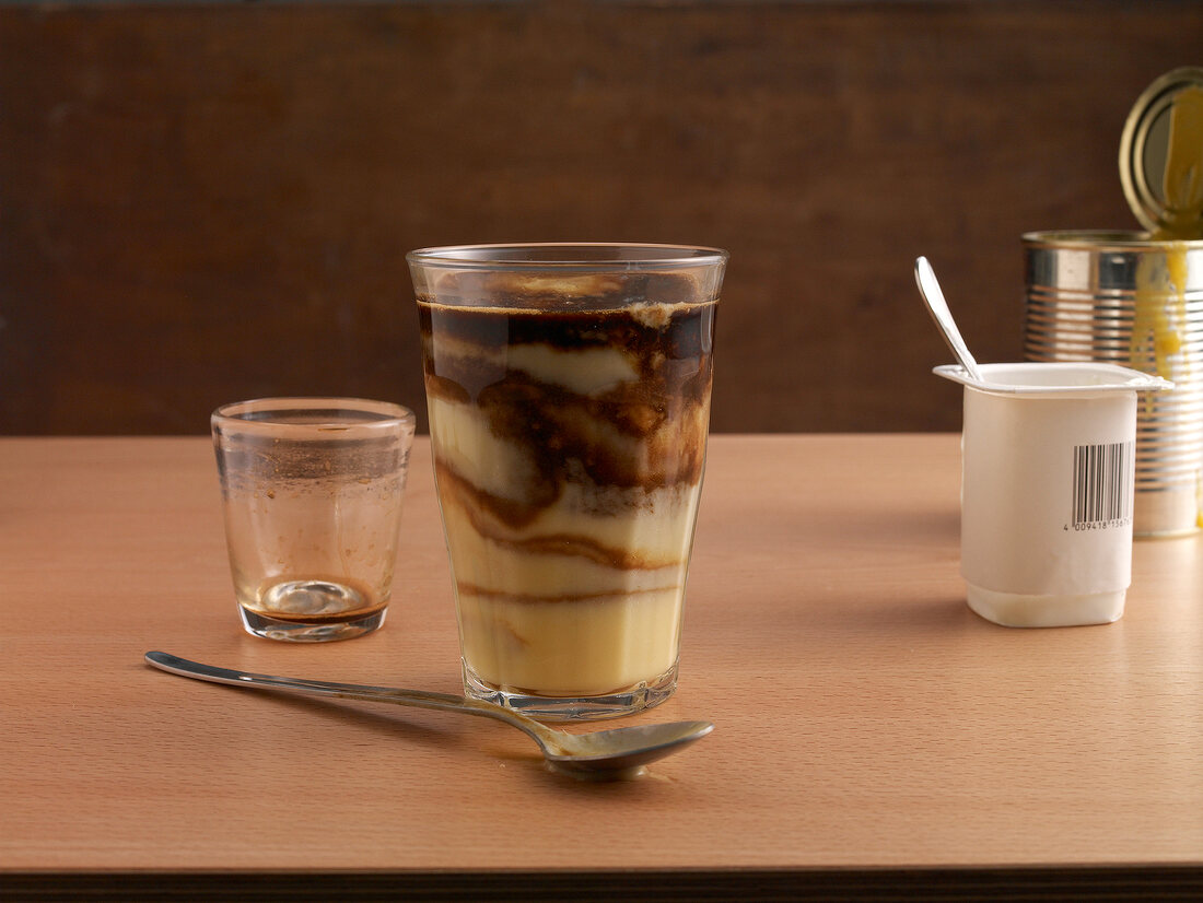 Glass of mango lassi with espresso, yogurt cups and empty glass on table