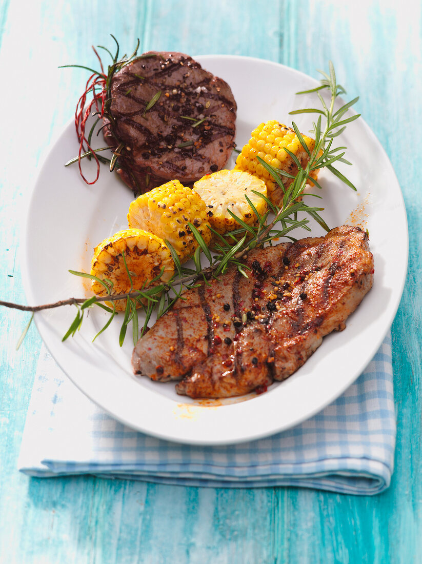 Marinated steak with roasted corn and sprig of rosemary on plate