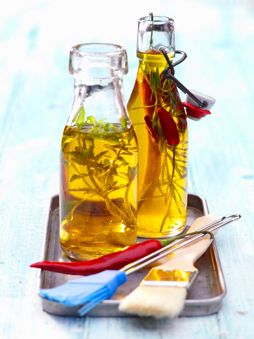 Two bottles of oil with rosemary and chili peppers