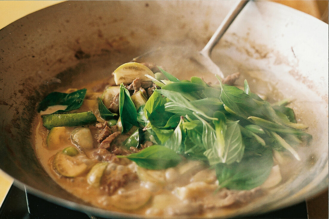 Thailändisch kochen, Curry im Wok, Thai-Basilikum zufügen