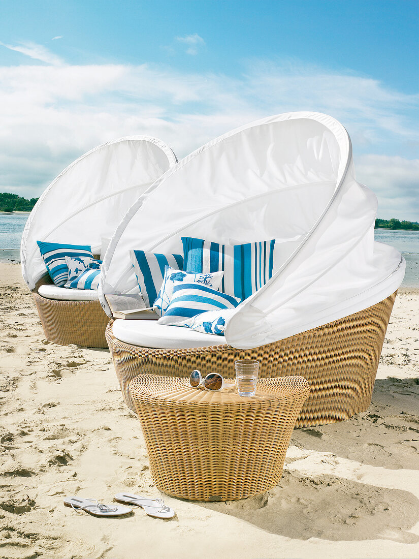 Two sofa islands with canopy and wicker table on beach