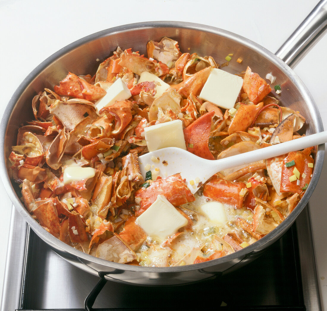 Butter with vegetables and lobster carcasses being cooked in wok, step 3