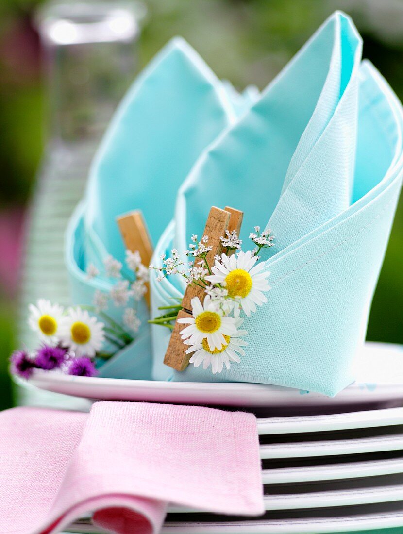 Napkins folded like bishop's mitres decorated with daisies and clothes pegs