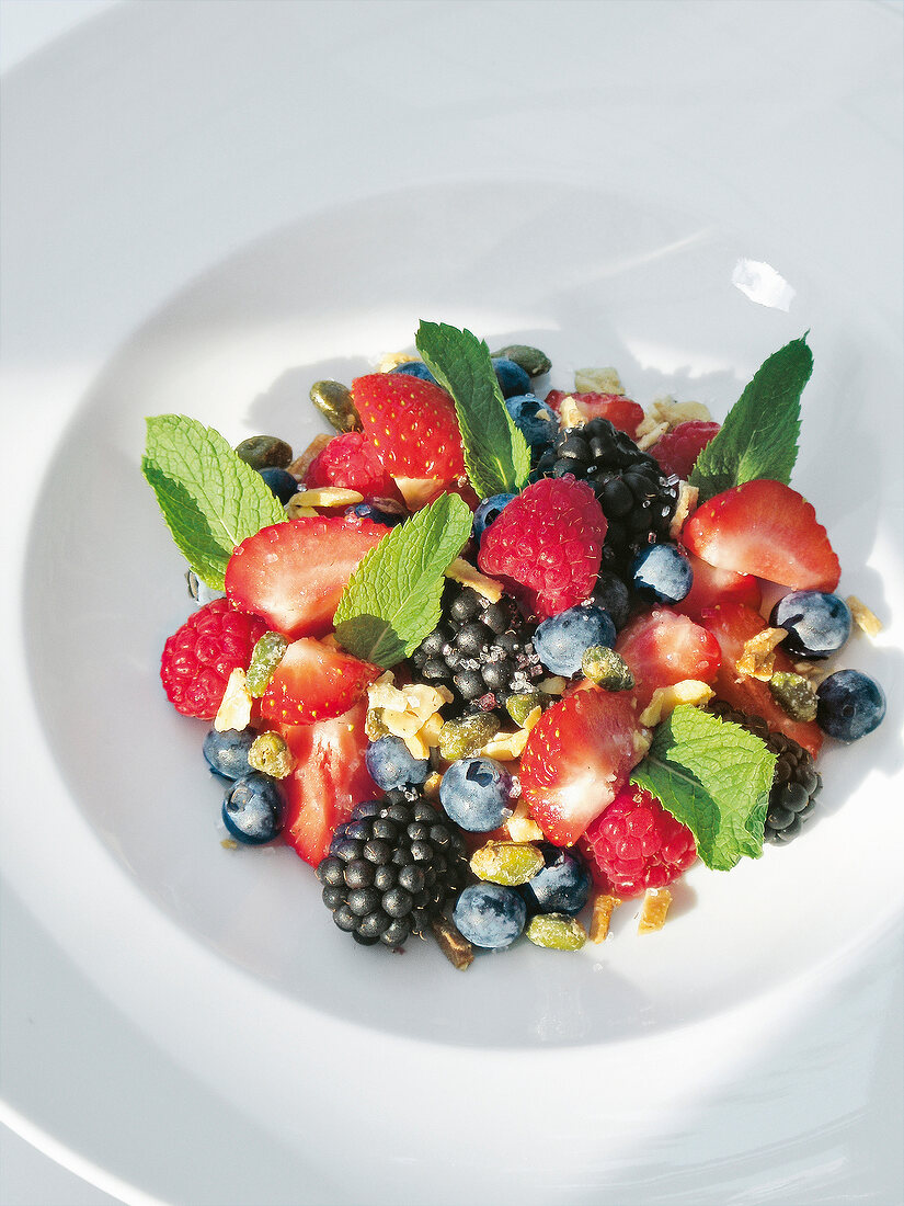 Close-up of fresh strawberries, raspberries, blackberries and mint in serving dish
