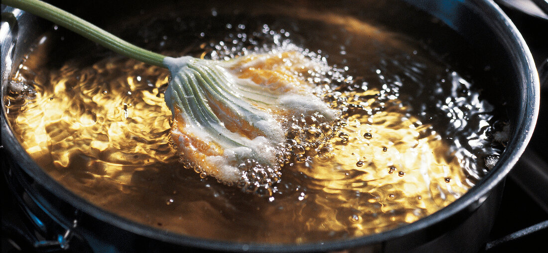 Close-up of zucchini blossom being fried