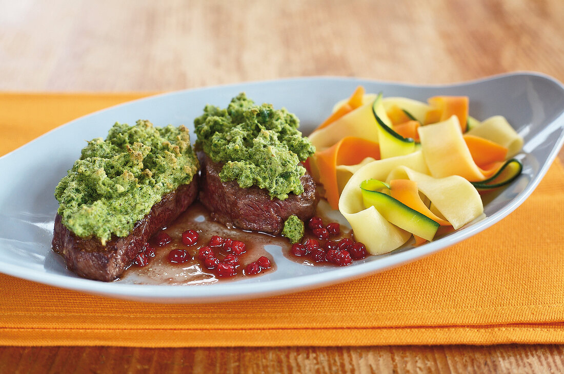 Venison medallions with nut and vegetable noodles in serving dish