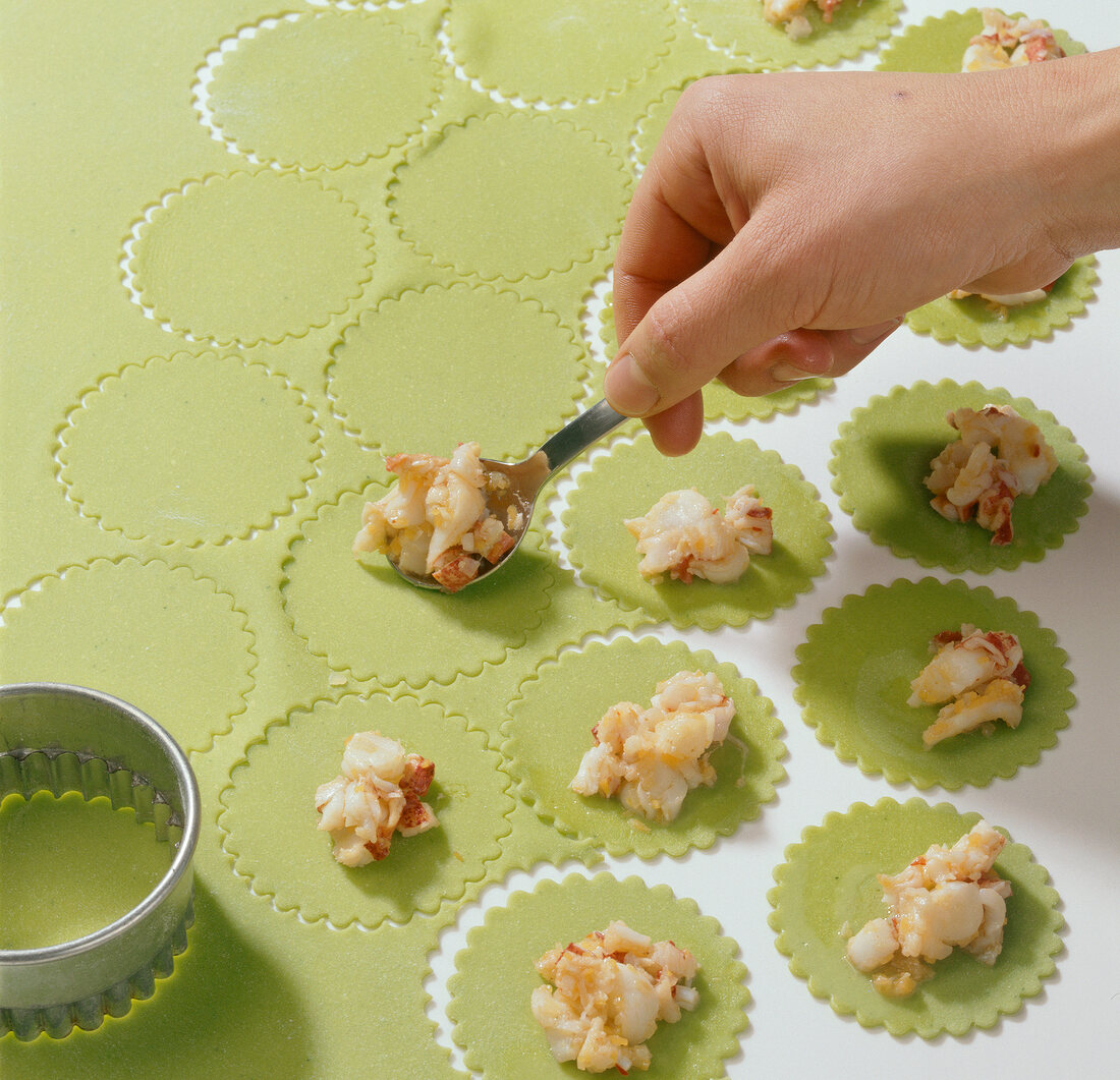 Dough circles being filled with lobster filling for preparation of lobster ravioli, step 2