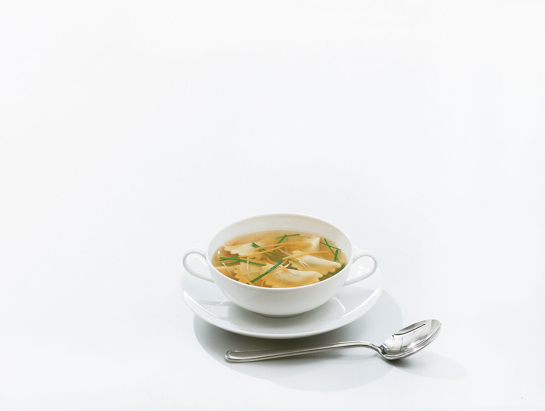 Soup with ravioli pasta in cup on white background