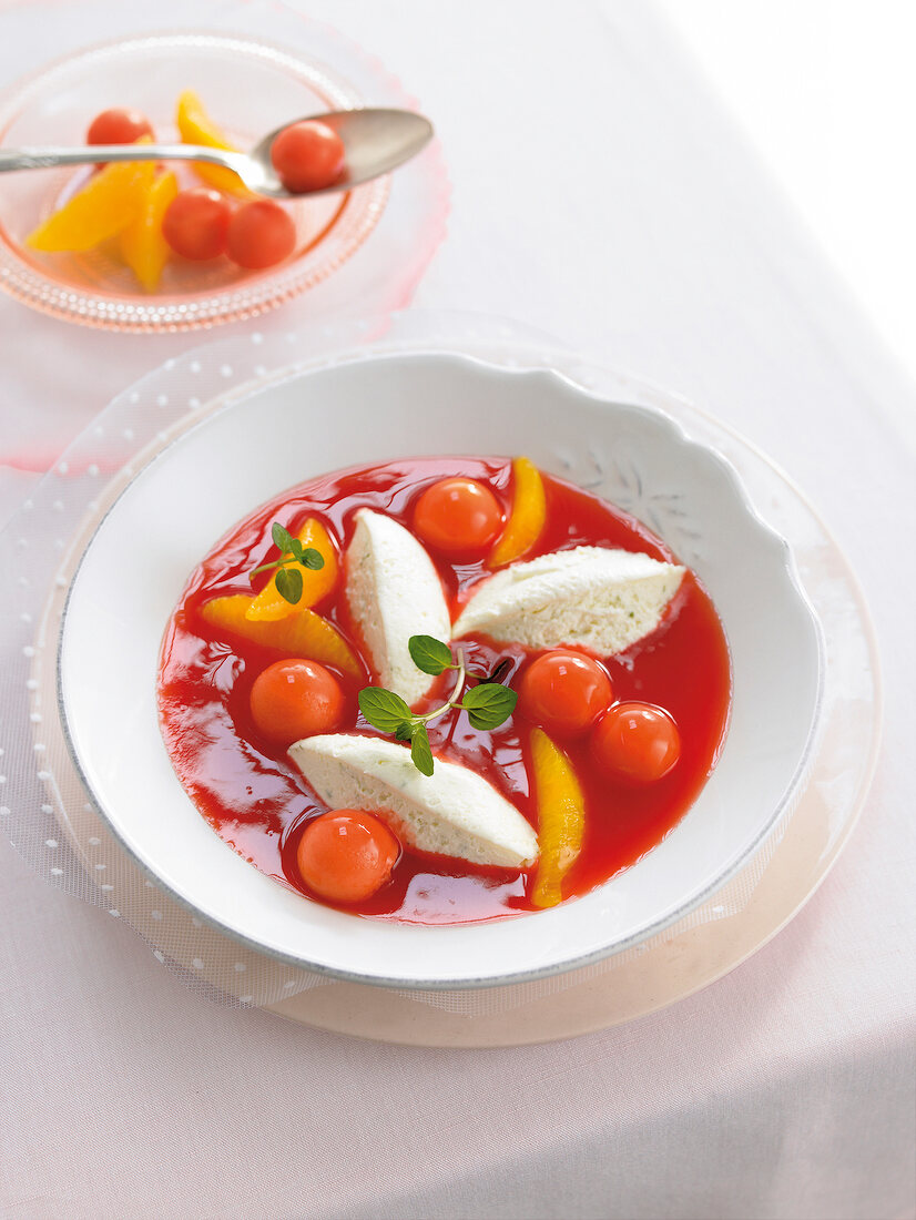 Fruit soup of blood orange and papaya with cream in bowl