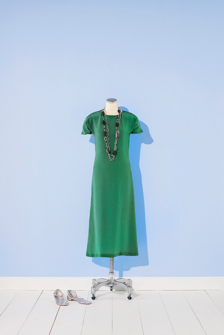 Green silk dress and necklace on mannequin