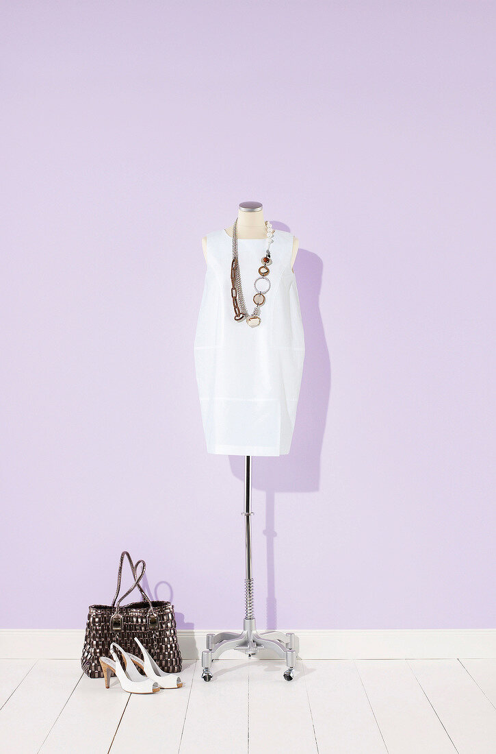 White satin dress and necklace on mannequin
